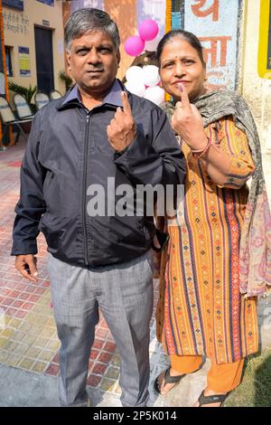 Neu-Delhi, Indien - Dezember 04 2022 - Unbekannte zeigen ihre mit Tinte markierten Finger, nachdem sie vor dem Wahlstand von Ost-Delhi Stimmen abgegeben haben Stockfoto