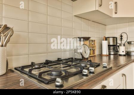 Eine Küche mit weißen Fliesen an den Wänden und Holzablagen vor dem Herd, der zum Kochen verwendet wird Stockfoto