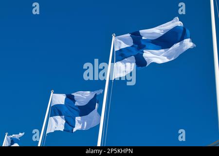 finnische Nationalflaggen im Wind gegen den blauen Himmel Stockfoto