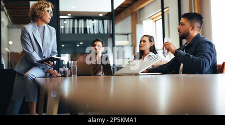 Das Business-Team diskutiert ein Projekt in einem Meeting mit seinem Manager. Gruppe von Geschäftsleuten, die in einem Sitzungssaal sitzen und sich unterhalten. Professioneller Designer Stockfoto