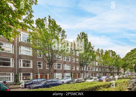 Amsterdam, Niederlande - 10. April 2021: Eine urbane Straße mit geparkten Autos und Fahrrädern in amsterdam, Niederlande, auf einem hellen Sonnenfoto von Shutterstocker Stockfoto