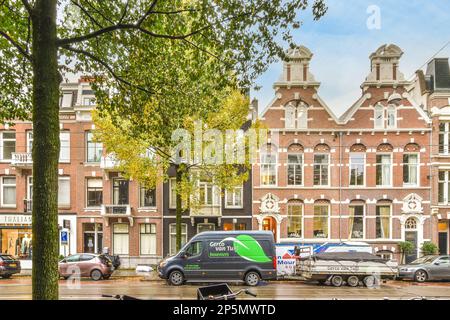 Eine Stadtstraße mit Autos, die an der Seite geparkt sind, und Gebäuden im Hintergrund, alle mit Sonnenschirmen bedeckt Stockfoto