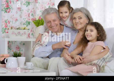 Großvater und Großmutter zusammen mit ihren Enkelinnen auf dem Sofa Stockfoto