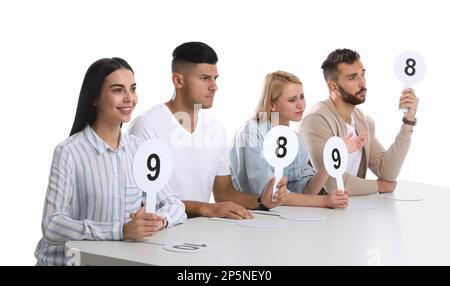 Jury-Gruppe mit unterschiedlichen Punktezeichen am Tisch auf weißem Hintergrund Stockfoto