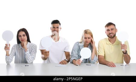 Jury-Gruppe mit unterschiedlichen Emotionen mit leeren Schildern am Tisch auf weißem Hintergrund. Platz für Text Stockfoto