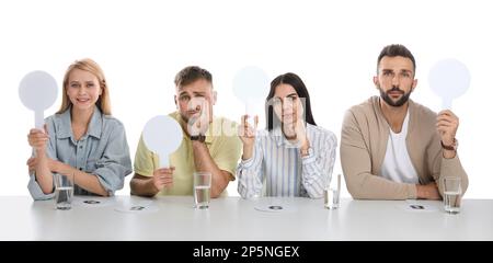 Jury-Gruppe mit unterschiedlichen Emotionen mit leeren Schildern am Tisch auf weißem Hintergrund. Platz für Text Stockfoto