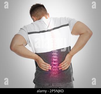Ein Mann mit Rückenschmerzen auf hellem Hintergrund. Digitales Compositing mit Darstellung der Wirbelsäule Stockfoto