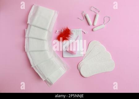 Menstruationseinlagen und andere Damenhygieneprodukte auf pinkfarbenem Hintergrund, flach liegend Stockfoto