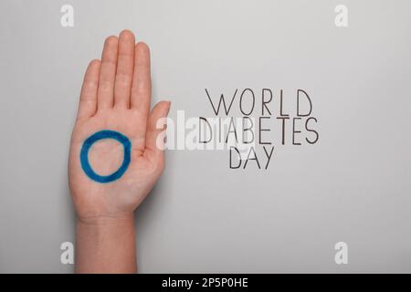 Frau mit Handfläche und blauem Kreis in der Nähe des Textes World Diabetes Day auf hellem Hintergrund, Nahaufnahme Stockfoto