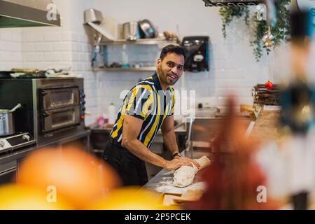 Junger Mann, der in der kommerziellen Küche frisches Essen zubereitet Stockfoto