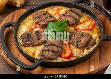 Fleischbällchen mit Alinazik-Sauce. Traditionelle türkische Fleischbällchen auf Auberginenpüree in gusseiserner Pfanne Stockfoto