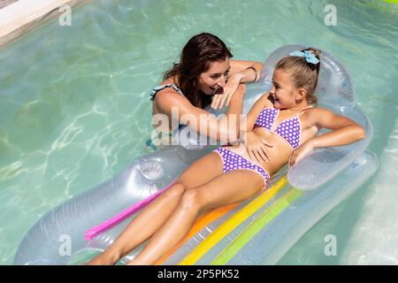 Glückliche, birassische Mutter und Tochter, die zusammen im Swimmingpool spielen Stockfoto
