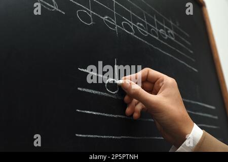 Lehrer schreibt Noten mit Kreide an der Tafel, Nahaufnahme Stockfoto