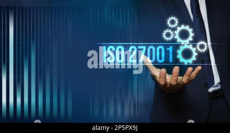 Mann demonstriert virtuelles Symbol mit Text ISO 27001, Nahaufnahme. Bannerdesign Stockfoto