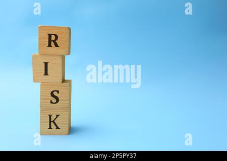 Stapel Holzwürfel mit Wortrisiko auf hellblauem Hintergrund. Platz für Text Stockfoto