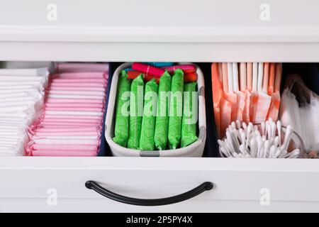 Offene Schrankschublade mit Menstruationsmatten, Tampons und Wattestäbchen, Nahaufnahme Stockfoto