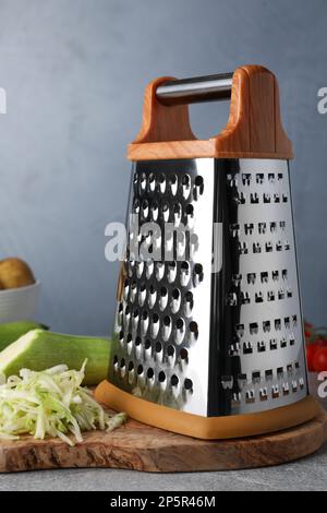 Reibe und frische Zucchini auf grauem Tisch Stockfoto