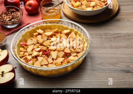 Rohteig und Zutaten für Apfelkuchen auf Holztisch Stockfoto