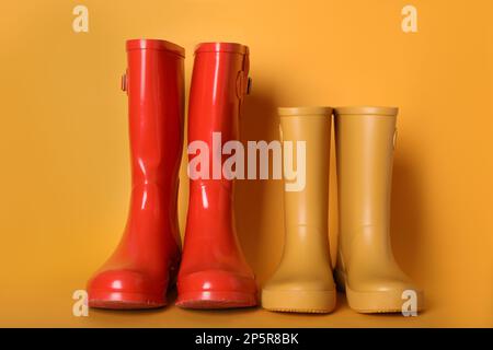 Zwei Paar Gummistiefel auf orangefarbenem Hintergrund Stockfoto