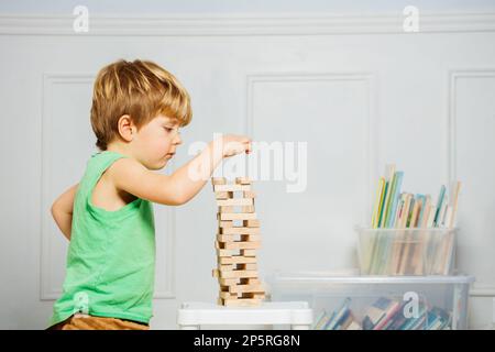 Nahaufnahme eines Jungen, der einen Turm baut und mit Jenga-Holzblöcken spielt Stockfoto
