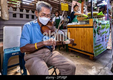 Ein alter thailändischer Musiker spielt Geige auf dem schwimmenden Markt von Lad Mayom, Bangkok, Thailand Stockfoto