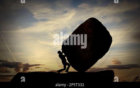 Ein Mann schiebt einen großen Felsen bei Sonnenuntergang. Konzept für harte Arbeit und schwere Aufgaben. Die Person rollt den Stein auf dem Berg Stockfoto