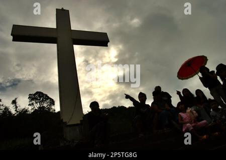 Silhouette von Besuchern und ein hohes christliches Kreuz im Bukit Kasih (Hügel der Liebe), einem beliebten religiösen Reiseziel im Dorf Kanonang, West Kawangkoan, Minahasa, North Sulawesi, Indonesien. Gewidmet allen religiösen Gläubigen und Gläubigen, während sie die Geister der Liebe, des Friedens und der Toleranz fördern; Bukit Kasih wurde Anfang 2000 gegründet, als Adolf J. Sondakh Gouverneur der Provinz Nord-Sulawesi war. Sie wurde als noble Friedensinitiative betrachtet; eine Reaktion auf Konflikte auf Grund der Religion und der ethnischen Zugehörigkeit geschah vor und um 2000 in mehreren anderen Provinzen. Stockfoto