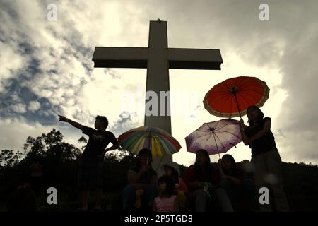 Silhouette von Besuchern und ein hohes christliches Kreuz im Bukit Kasih (Hügel der Liebe), einem beliebten religiösen Reiseziel im Dorf Kanonang, West Kawangkoan, Minahasa, North Sulawesi, Indonesien. Gewidmet allen religiösen Gläubigen und Gläubigen, während sie die Geister der Liebe, des Friedens und der Toleranz fördern; Bukit Kasih wurde Anfang 2000 gegründet, als Adolf J. Sondakh Gouverneur der Provinz Nord-Sulawesi war. Sie wurde als noble Friedensinitiative betrachtet; eine Reaktion auf Konflikte auf Grund der Religion und der ethnischen Zugehörigkeit geschah vor und um 2000 in mehreren anderen Provinzen. Stockfoto