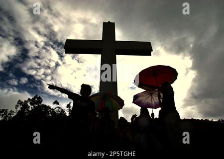 Silhouette von Besuchern und ein hohes christliches Kreuz im Bukit Kasih (Hügel der Liebe), einem beliebten religiösen Reiseziel im Dorf Kanonang, West Kawangkoan, Minahasa, North Sulawesi, Indonesien. Gewidmet allen religiösen Gläubigen und Gläubigen, während sie die Geister der Liebe, des Friedens und der Toleranz fördern; Bukit Kasih wurde Anfang 2000 gegründet, als Adolf J. Sondakh Gouverneur der Provinz Nord-Sulawesi war. Sie wurde als noble Friedensinitiative betrachtet; eine Reaktion auf Konflikte auf Grund der Religion und der ethnischen Zugehörigkeit geschah vor und um 2000 in mehreren anderen Provinzen. Stockfoto