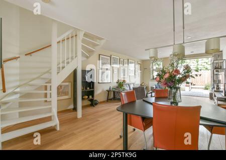 Amsterdam, Niederlande - 10. April 2021: Ein Speisesaal mit Holzfußboden und weißer Treppe, die in die zweite Etage in einem offenen Haus führt Stockfoto