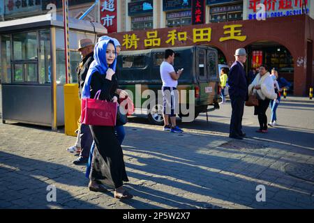 Einwohner mit traditionellen uigurischen Turbans und quadratischen Mützen auf den Straßen von Urumqi, Xinjiang, China Stockfoto