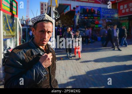 Einwohner mit traditionellen uigurischen Turbans und quadratischen Mützen auf den Straßen von Urumqi, Xinjiang, China Stockfoto