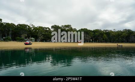 Blick vom Coochiemudlo Jetty, zurück über das wunderschöne, reflektierende, ruhige Wasser in Richtung Sandstrand Stockfoto