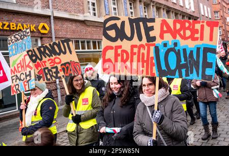 07. März 2023, Mecklenburg-Vorpommern, Schwerin: Teilnehmer eines Warnstreiks von Mitarbeitern der Bundes- und Kommunalverwaltung marschieren durch die Schweriner Innenstadt mit Schildern mit der Aufschrift "bessere Bedingungen, qualifiziertere Arbeiter", "Burnout um 30 Uhr". 1Erz:33Kd" und "gute Arbeit, fairer Lohn". Die Gewerkschaft Verdi hat die Beschäftigten in 40 Kindertagesstätten und vier Kindertagesstätten in West-Mecklenburg aufgefordert, zu streiken, um den Druck auf die Arbeitgeber im Lohnstreit im öffentlichen Sektor zu erhöhen. (Zu dpa 'Warnung schlägt in 40 Kindertagesstätten in West-Mecklenburg - die meisten bleiben geschlossen' Stockfoto