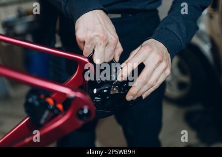 Mechaniker, der mit einem Schraubenschlüssel ein Sonderfahrrad in der Werkstatt zusammenbaut Stockfoto