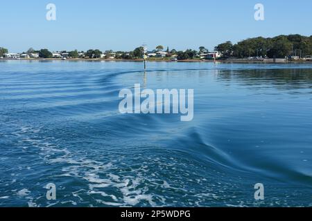 Blick vom Kutschboot Coochiemudlo Island über das Wasser zum Victoria Point mit Wellen im Gefolge des Kutschers. Stockfoto