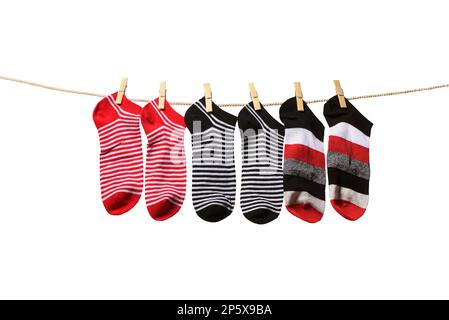 Saubere, gewaschene, gestreifte Socken, die an einem Seil hängen, isoliert auf weißem Hintergrund. Wäscheleine mit roten, grauen und weißen Socken Stockfoto