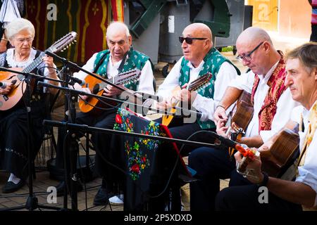 Musiker in traditionellen Kleidern spielen Streichinstrumente auf einer Fiesta in Spanien Stockfoto