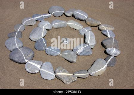 Steinkreise auf Sand aus Steinen mit weißen Streifen, kleiner Kiesel in der Mitte Stockfoto