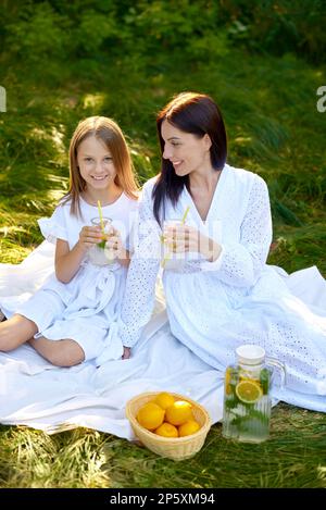 Kind Mädchen Kind und Frau halten ein Glas Limonade in den Händen und Getränke beim Picknick Stockfoto