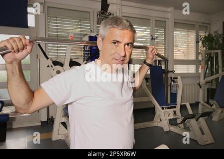 Der ältere Mann trainiert auf dem lat Pulldown im Fitnessstudio Stockfoto