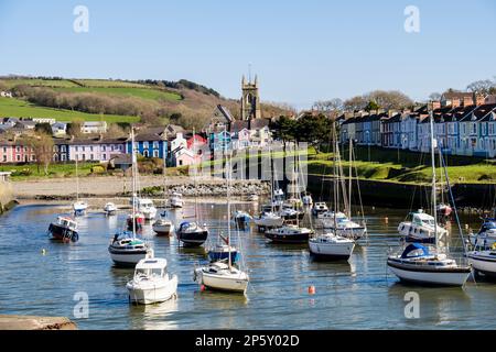 Blick entlang der Afon Aeron River Mündung zur Kirche mit Booten im Hafen bei einer Flut in attraktiven Küstenstadt festgemacht. Aberaeron Ceredigion Wales Stockfoto