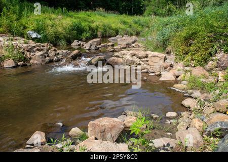 Wasser fließt in Strömen über die Ruinen eines alten Dammes aus Kolonail-Stein Stockfoto