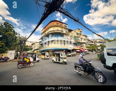 Eine Menge Telefon- und Stromkabel hängen an einer Straßenkreuzung neben einem alten Apartmentgebäude im Zentrum von Phnom Penh, Kambodscha. Stockfoto