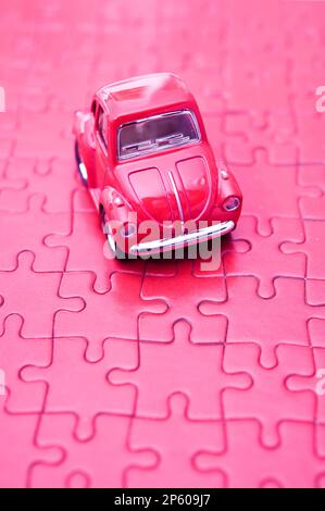 Pinkfarbenes Spielzeugauto auf einem pinken Puzzle Stockfoto