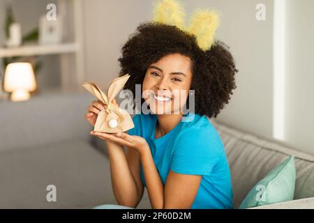 Porträt einer wunderschönen, jungen schwarzen Frau mit ostergeschenktasche zu Hause Stockfoto