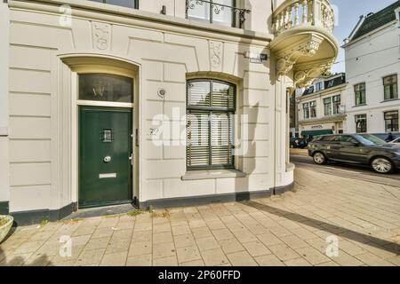 Ein altes Gebäude mit einer grünen Tür und Fensterläden an der Seite des Gebäudes steht ein Auto davor Stockfoto