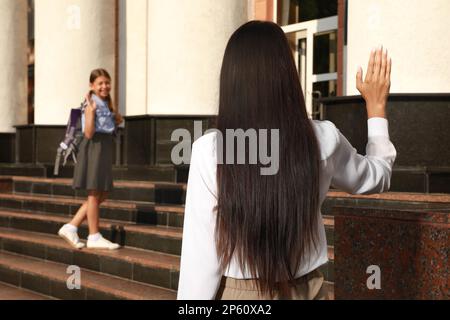 Mutter winkte ihrer Tochter in der Nähe des Schuleingangs zu Stockfoto