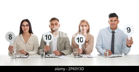 Jury-Gruppe mit unterschiedlichen Punktezeichen am Tisch auf weißem Hintergrund Stockfoto