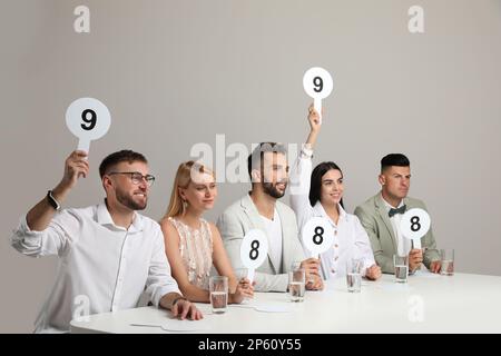 Jury mit unterschiedlichen Punktezeichen am Tisch auf beigefarbenem Hintergrund Stockfoto